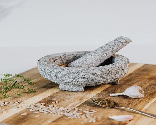 Vintage style photo of traditional mortar and pestle with garlic and herbs