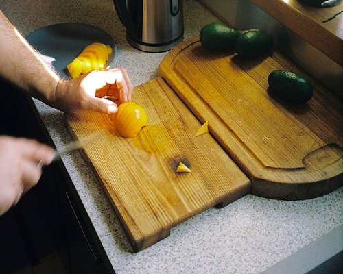 Chef hands chopping fresh garlic cloves on a cutting board